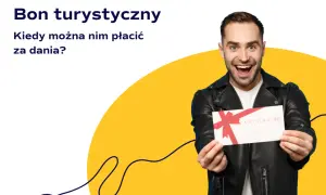 Uśmiechnięty mężczyzna trzyma bon podarunkowy. Czy bon turystyczny można wykorzystać w restauracji na pyszne dania?