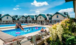 Rodzinny wypoczynek w domkach apartamentowych Fulay Premium. Dzieci bawią się w basenie ze zjeżdżalnią, dorośli relaksują się na leżakach.