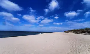 Piękny, pusty piasek i błękitne niebo z chmurami. Idealne miejsce na wyjazd nad morze.