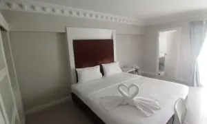 Elegancki pokój hotelowy z łóżkiem ozdobionym ręcznikami w kształcie łabędzi. Idealne miejsce, gdzie szukać noclegu na wakacje.