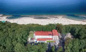 Tanie noclegi Darłówko: hotel otoczony lasem, blisko plaży pełnej turystów. Idealne miejsce na wakacje nad morzem.