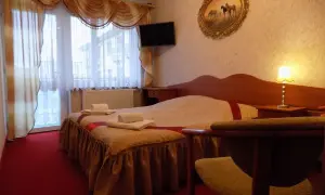 Przytulny pokój w pensjonacie Angela Łeba. Łóżko z czystymi ręcznikami, obraz z końmi i lampka nocna.