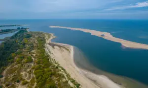 Piaszczyste mierzeje i zielone wybrzeże tworzą malowniczy krajobraz, idealny dla miast nad morzem.