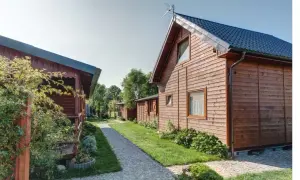 Drewniane domki letniskowe, idealne na wicie nad morzem. Ścieżka z kostki brukowej prowadzi między zielonymi trawnikami a budynkami.