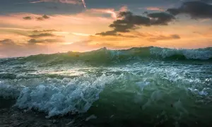 Fala za falą, tak jak piszemy morze, rozbijają się o brzeg. Zachód słońca maluje niebo na pomarańczowo.
