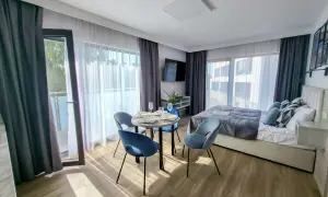 Przytulny pokój w hotelu gorzelanny Dźwirzyno. Łóżko, stolik z krzesłami i balkon.
