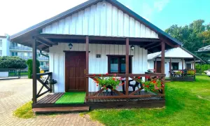 Urocze domki letniskowe Amber House z werandą i kwitnącymi pelargoniami. Idealne miejsce na wypoczynek.