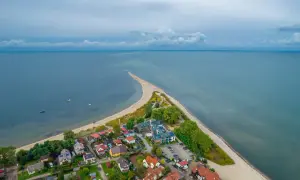 Malownicza miejscowość na wybrzeżu bałtyckim, z domkami i hotelem, otoczona plażą i morzem.