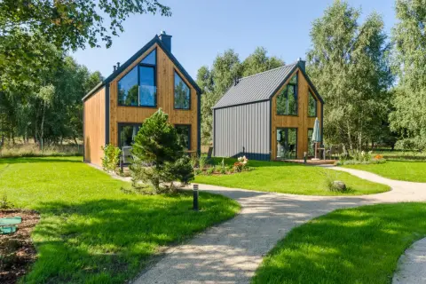 Nowe, nowoczesne domki w lesie nad morzem, otoczone zielenią i ścieżkami.