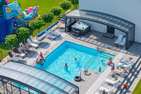 Relaks w apartamentach nad morzem z basenem. Dzieci bawią się na dmuchanym zamku, dorośli odpoczywają przy basenie i w jacuzzi.