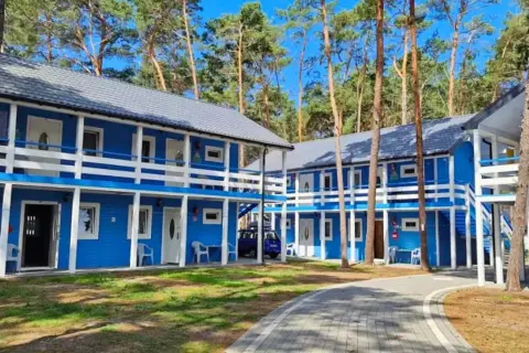 Niebieskie domki letniskowe w lesie, idealne na dziwnów noclegi blisko morza. Dostępne pokoje na parterze i piętrze z balkonami.