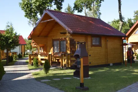 Drewniane domki letniskowe z czerwonymi dachami, idealne na wypoczynek. Sianożęty domki przy plaży czekają na gości.
