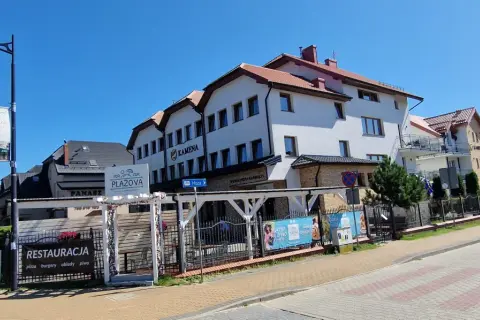 Ośrodek Kamena Karwia to biały budynek z czerwonym dachem, obok restauracja Plażova.