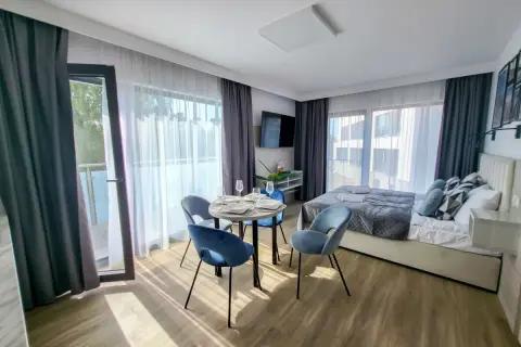 Przytulny pokój w hotelu gorzelanny Dźwirzyno. Łóżko, stolik z krzesłami i balkon.