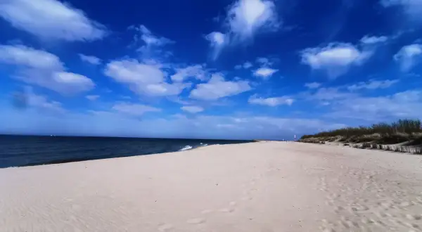 Piękny, pusty piasek i błękitne niebo z chmurami. Idealne miejsce na wyjazd nad morze.
