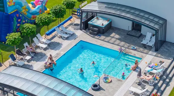 Relaks w apartamentach nad morzem z basenem. Dzieci bawią się na dmuchanym zamku, dorośli odpoczywają przy basenie i w jacuzzi.