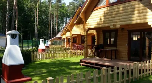 Nawrapark Pobierowo domki letniskowe: drewniane domki z tarasami i grillami, otoczone zielenią i lasem.