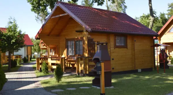 Drewniane domki letniskowe z czerwonymi dachami, idealne na wypoczynek. Sianożęty domki przy plaży czekają na gości.