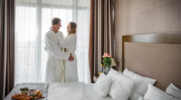 Para dwojga w szlafrokach przy oknie, z widokiem na morze. Idealne fajne miejsce nad morzem dla dwojga na romantyczny wypad.