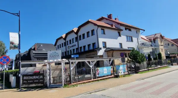 Ośrodek Kamena Karwia to biały budynek z czerwonym dachem, obok restauracja Plażova.