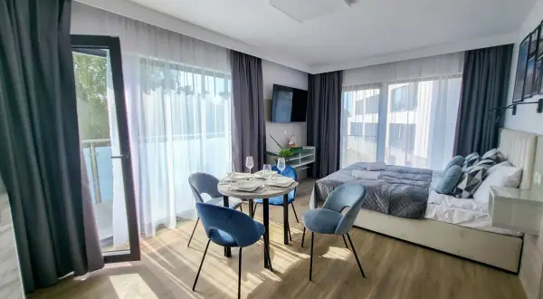 Przytulny pokój w hotelu gorzelanny Dźwirzyno. Łóżko, stolik z krzesłami i balkon.