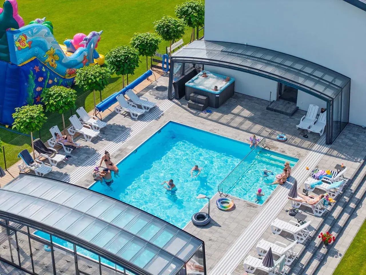 Relaks w apartamentach nad morzem z basenem. Dzieci bawią się na dmuchanym zamku, dorośli odpoczywają przy basenie i w jacuzzi.