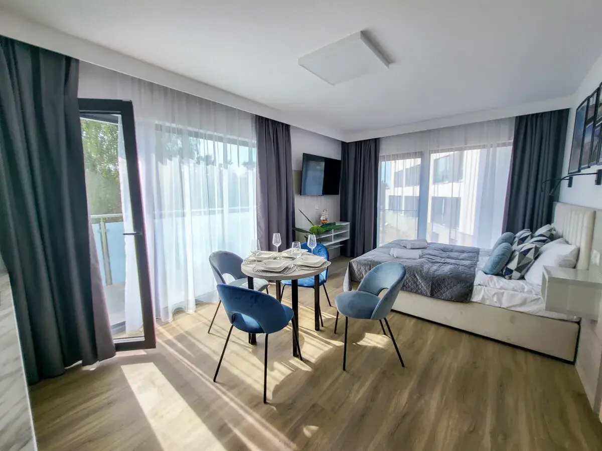 Przytulny pokój w hotelu gorzelanny Dźwirzyno. Łóżko, stolik z krzesłami i balkon.