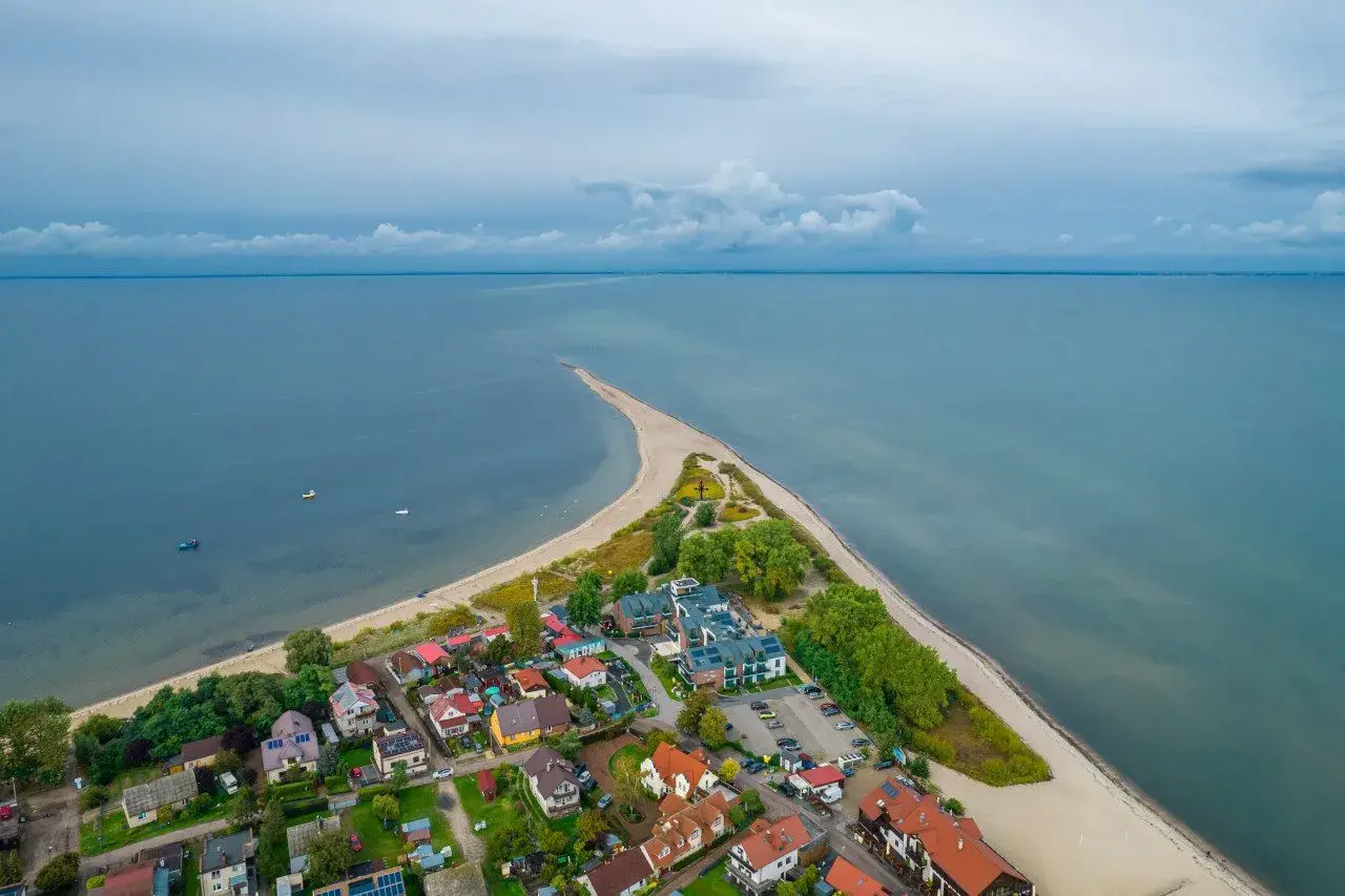Malownicza miejscowość na wybrzeżu bałtyckim, z domkami i hotelem, otoczona plażą i morzem.
