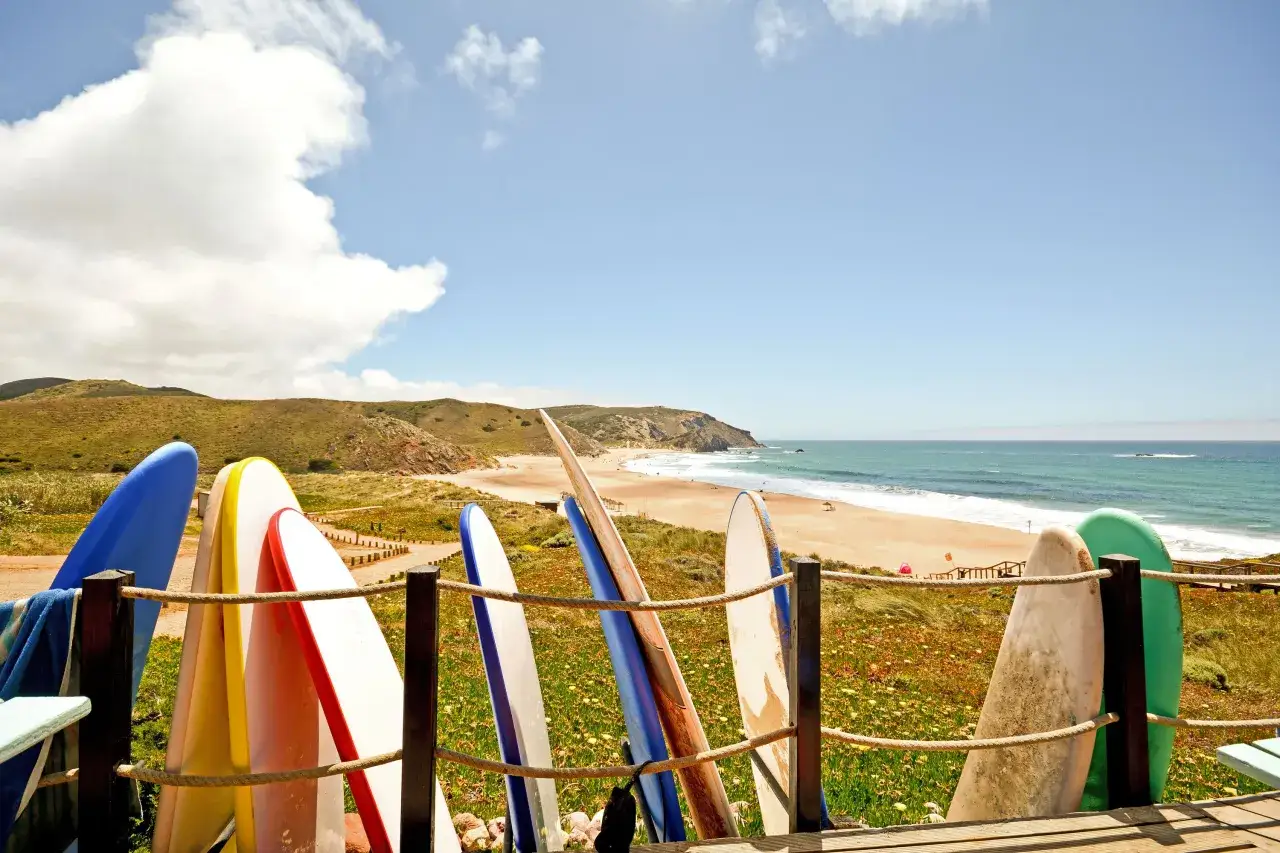 Deska surfingowa na tle plaży i oceanu. To dowód, że Portugalia ma dostęp do morza i jest rajem dla surferów.