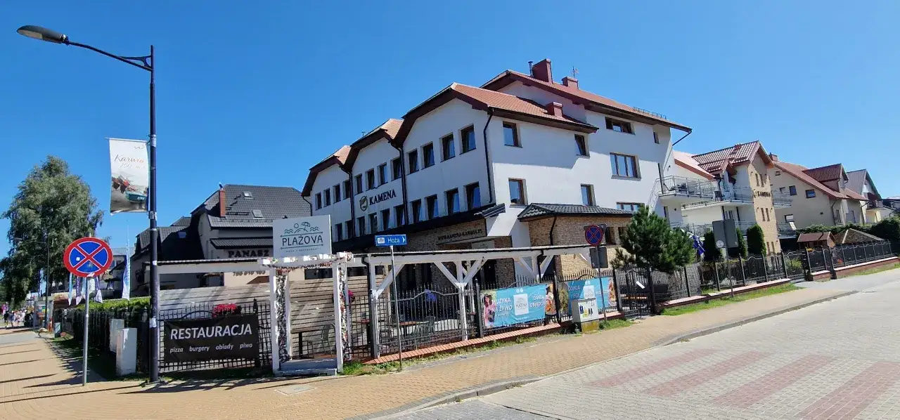 Ośrodek Kamena Karwia z restauracją i placem zabaw. W tle białe budynki z czerwonymi dachami.