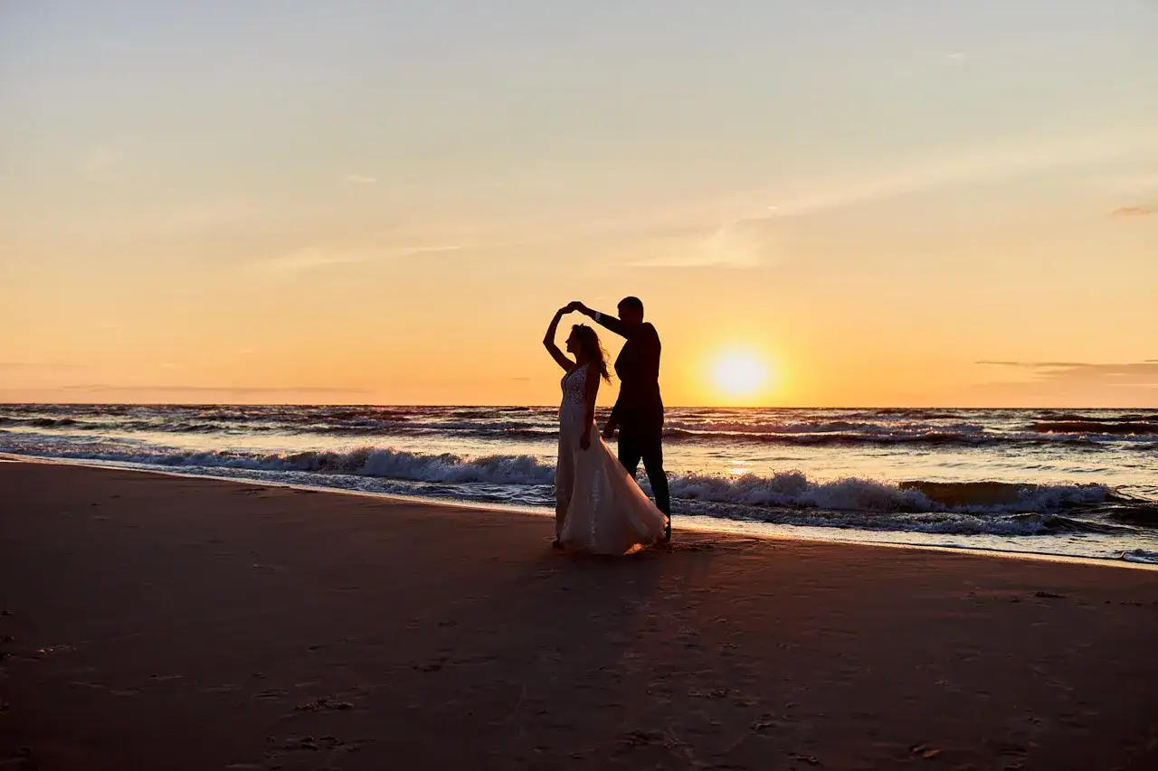 Para tańczy na plaży o zachodzie słońca. Romantyczny widok, idealne fajne miejsce nad morzem dla dwojga.