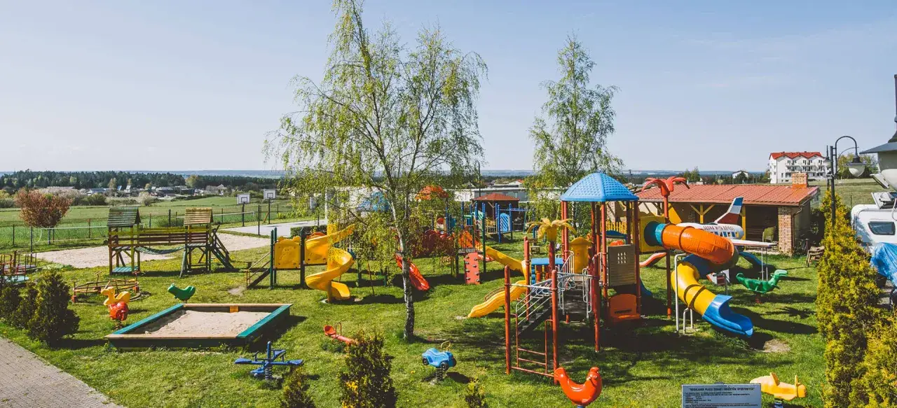 Kolorowy plac zabaw z zjeżdżalniami, huśtawkami i piaskownicą. To idealne miejsce na wypoczynek dla dzieci w kompleksie wypoczynkowym Sedna.