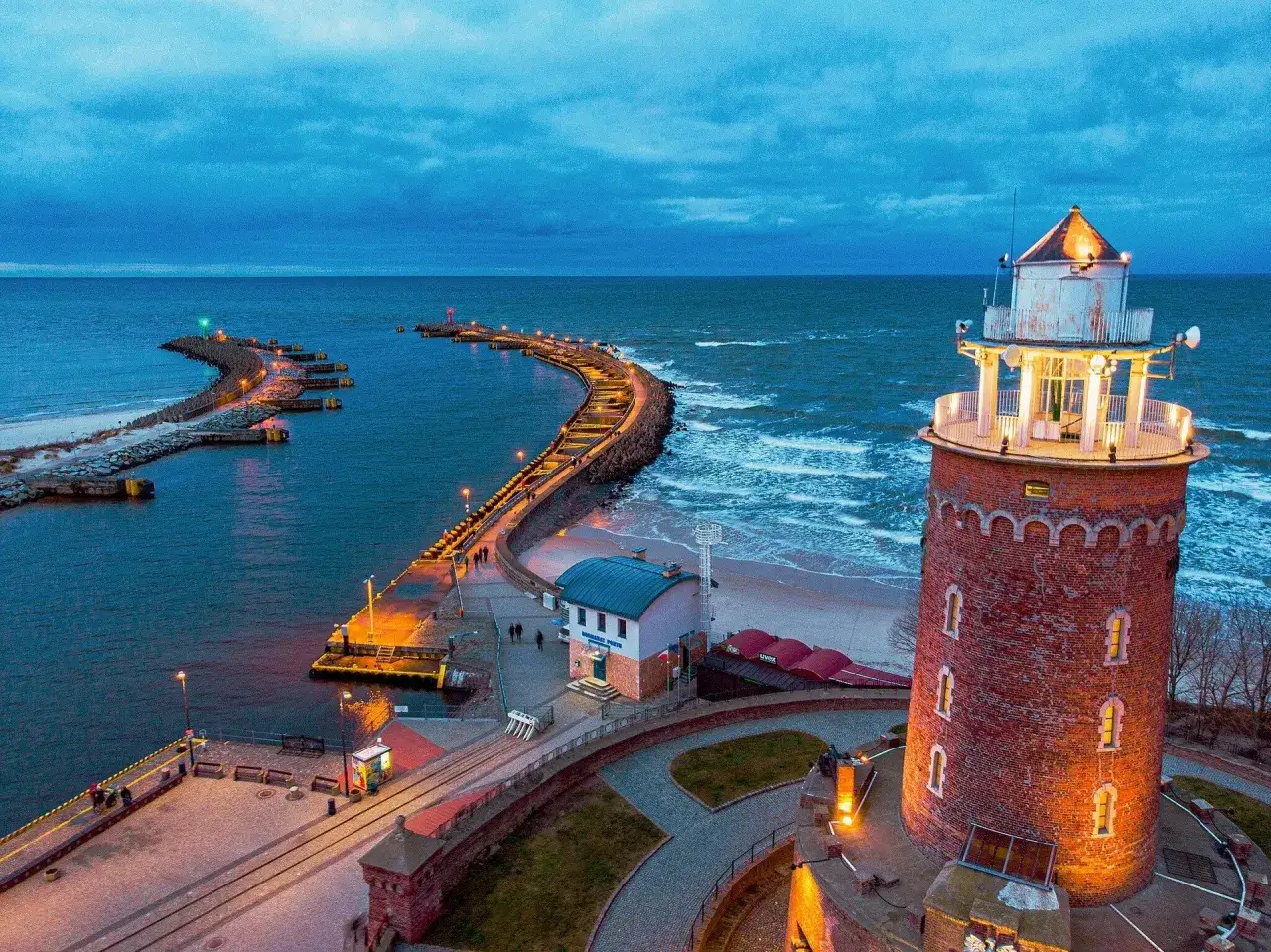 Latarnia morska i falochron o zmierzchu. Idealne miejsce, gdzie nad morze żeby się nie nudzić, spacerując po molo.