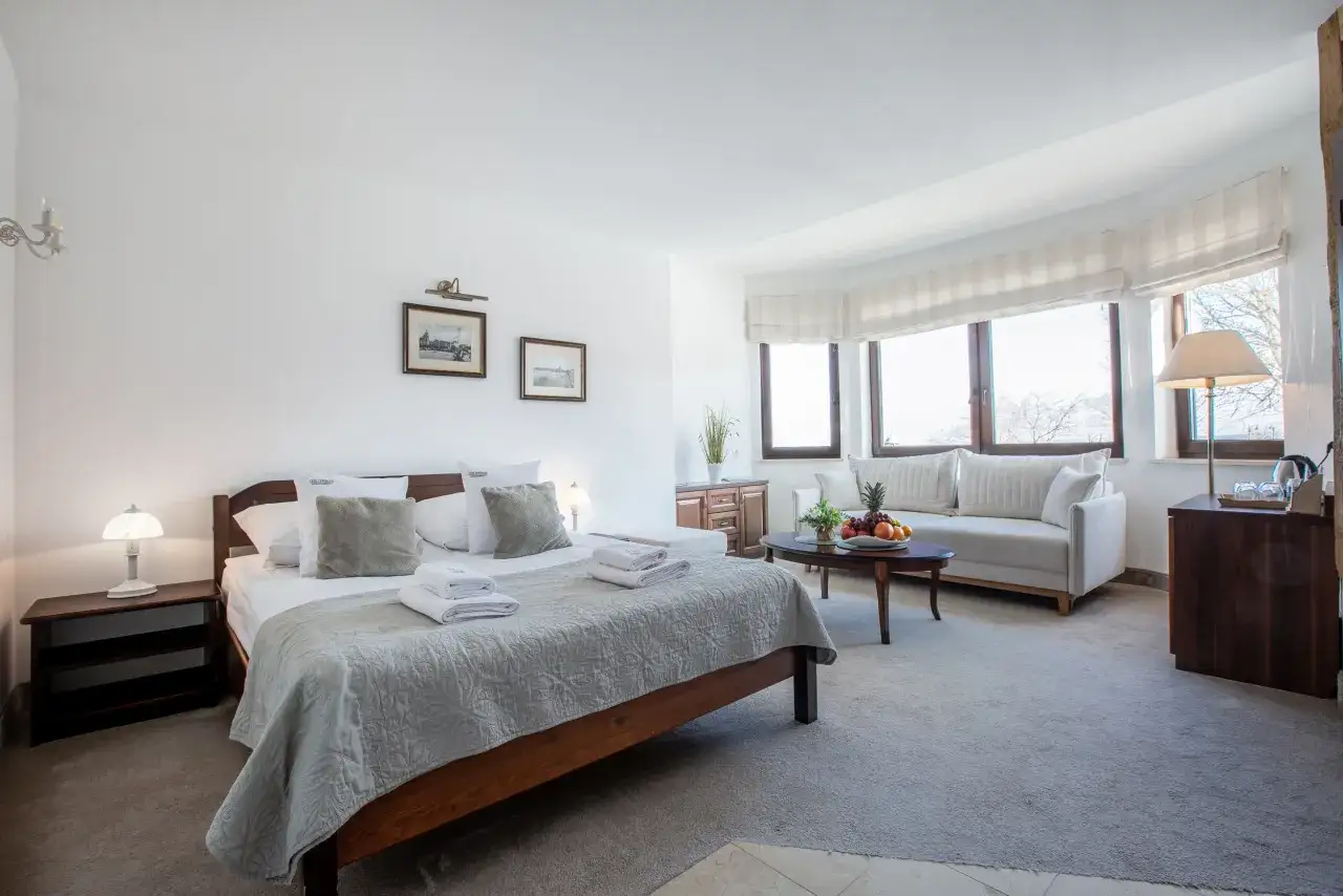 Przytulny apartament w Ustce. Duże łóżko, wygodna sofa i stolik z owocami. Idealne miejsce na wypoczynek w Columbus Apartamenty Ustka.