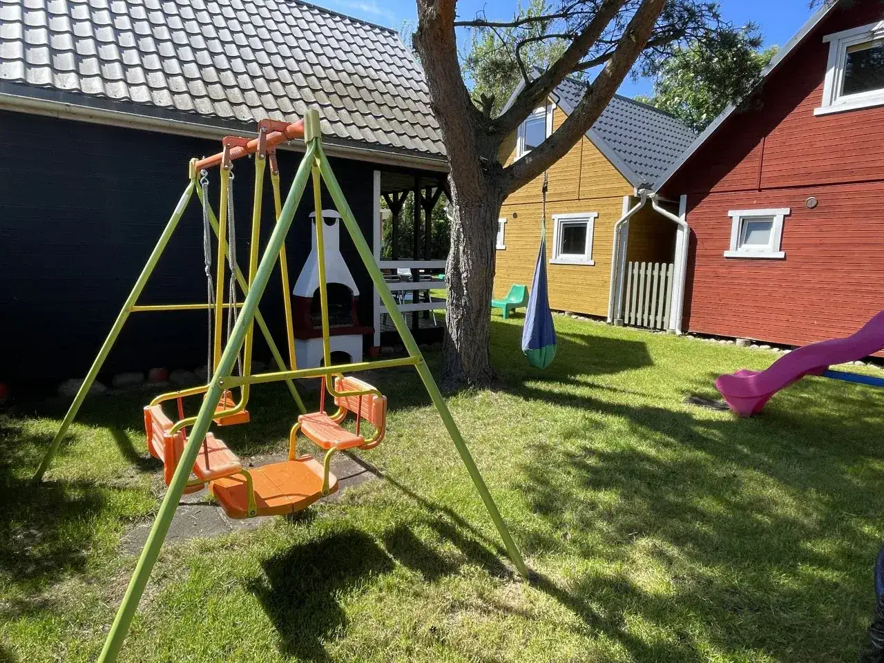 Kolorowe domki Jastrzębia Góra z huśtawką i zjeżdżalnią tworzą radosny plac zabaw dla dzieci.
