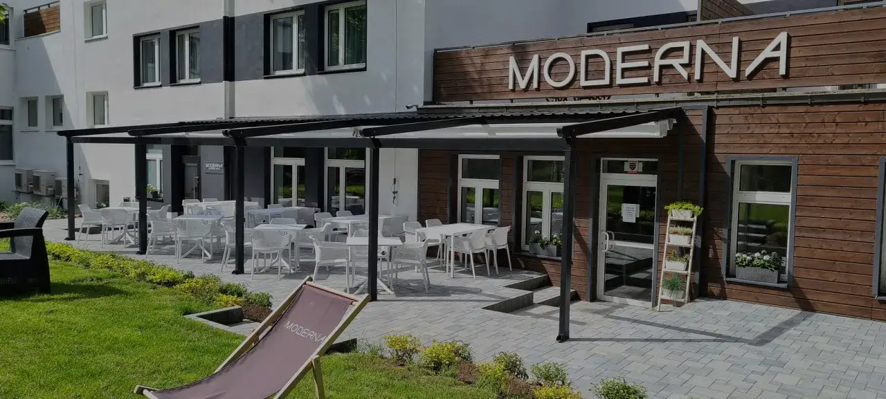 Nowoczesna jastrzębia góra zaprasza do wypoczynku na tarasie z białymi stolikami i krzesłami.