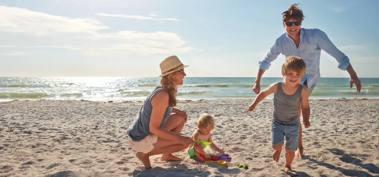 Radosny wyjazd nad morze. Rodzina bawi się na plaży, budując zamki z piasku. Słońce, piasek i uśmiechy dzieci.