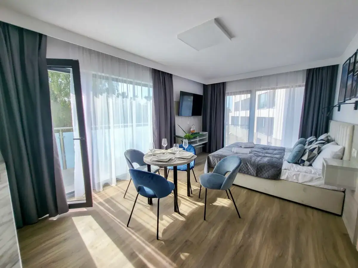 Przytulny pokój w hotelu gorzelanny Dźwirzyno. Łóżko, stolik z krzesłami i balkon.