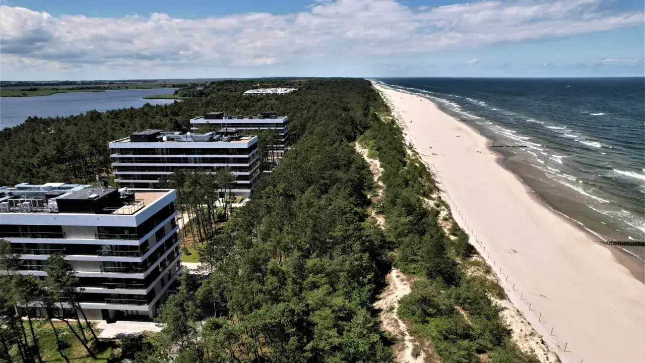 Nowoczesne apartamentowce w otoczeniu sosnowego lasu, tuż przy szerokiej, piaszczystej plaży. Rogowo nad morzem w pełnej krasie.
