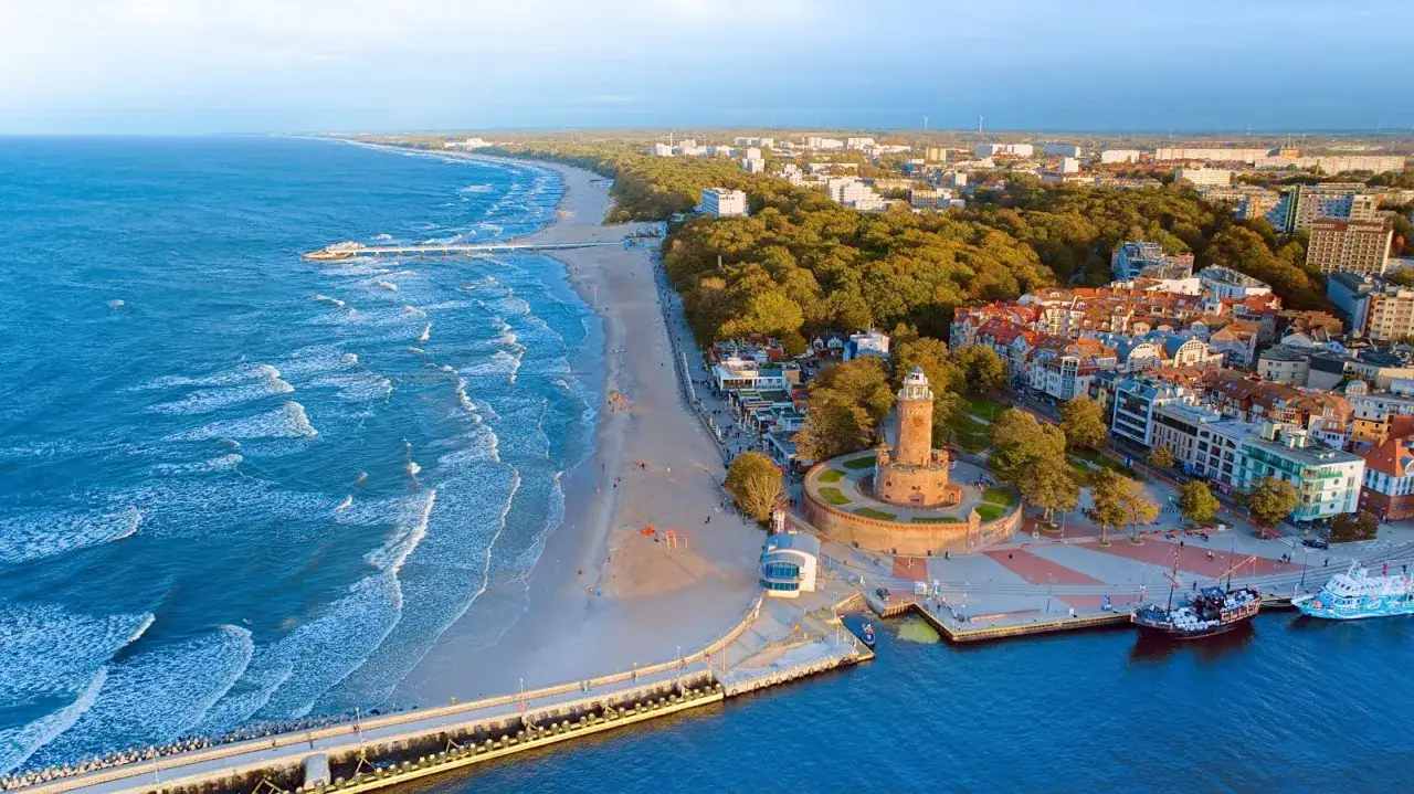 Kołobrzeg co warto zobaczyć: latarnia morska, molo, plaża i port z widokiem na Bałtyk.
