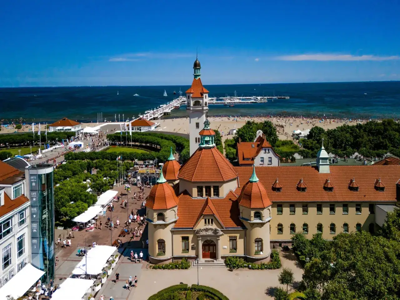 Piękne szpitale rehabilitacyjne nad morzem NFZ w Sopocie. Tłumy ludzi na plaży i molo.