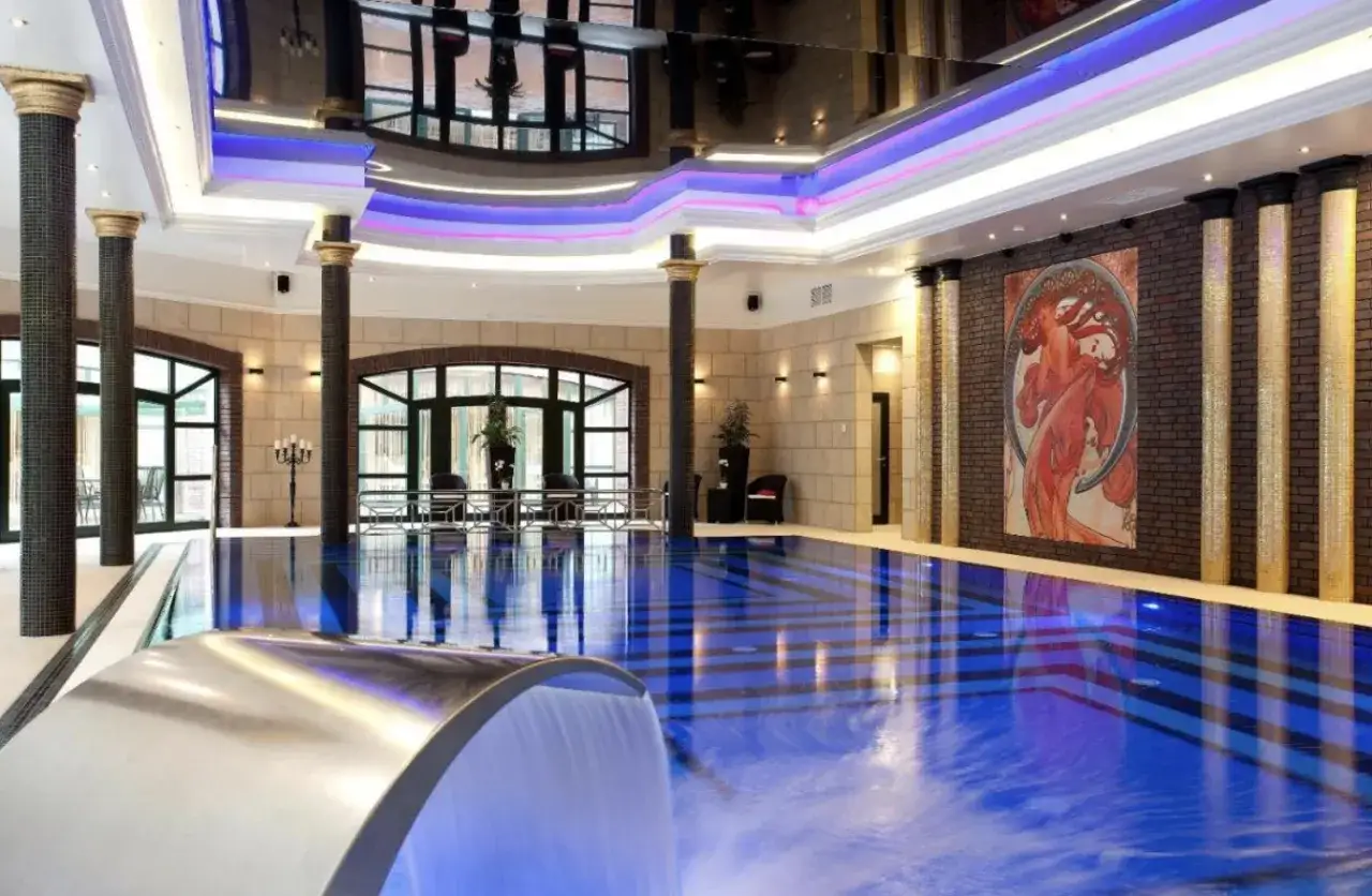 Luksusowy basen w hotelu nad morzem bałtyckim. Woda w basenie ma niebieski kolor, a na ścianie wisi obraz w stylu art déco.