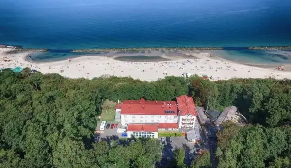 Widok z lotu ptaka na resort spa plaza otoczony lasem, z plażą i morzem w tle.