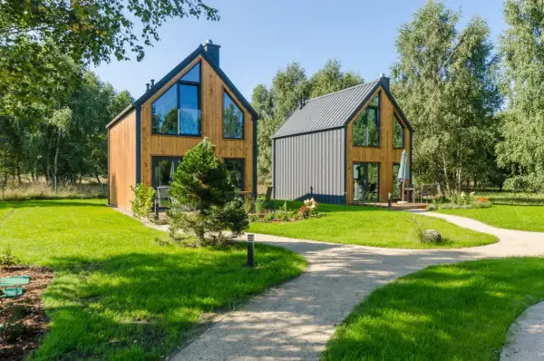 Nowe, nowoczesne domki w lesie nad morzem, otoczone zielenią i ścieżkami.