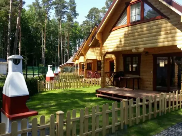 Nawrapark Pobierowo domki letniskowe: drewniane domki z tarasami i grillami, otoczone zielenią i lasem.