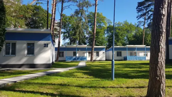 Urocze domki letniskowe w Międzyzdrojach, otoczone zielenią, zapraszają na wypoczynek. Numer 21 widoczny na jednym z budynków.