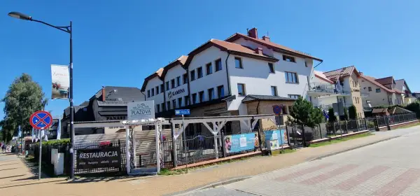 Ośrodek Kamena Karwia to biały budynek z czerwonym dachem, obok restauracja Plażova.