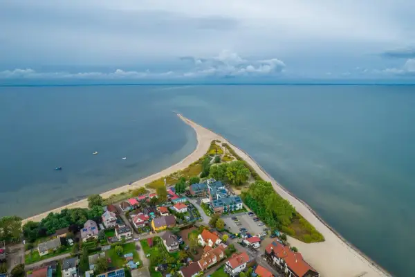 Malownicza miejscowość na wybrzeżu bałtyckim, z domkami i hotelem, otoczona plażą i morzem.