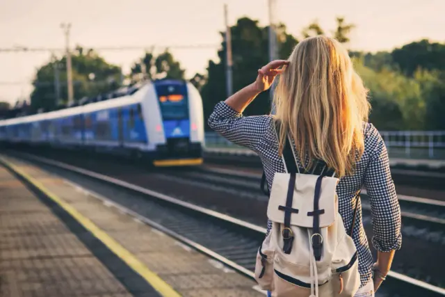 Dziewczyna z plecakiem czeka na pociąg, który zabierze ją gdzie nad morze pociągiem.